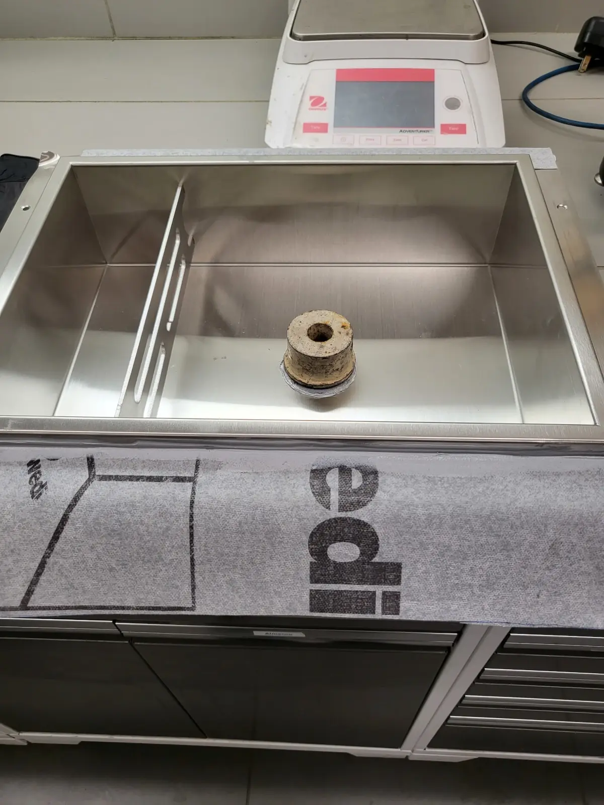 Wedi laboratory photograph from Product/Process Test Report 2101 showing adhesion-test specimens on the Redblock stainless-steel niche surface.