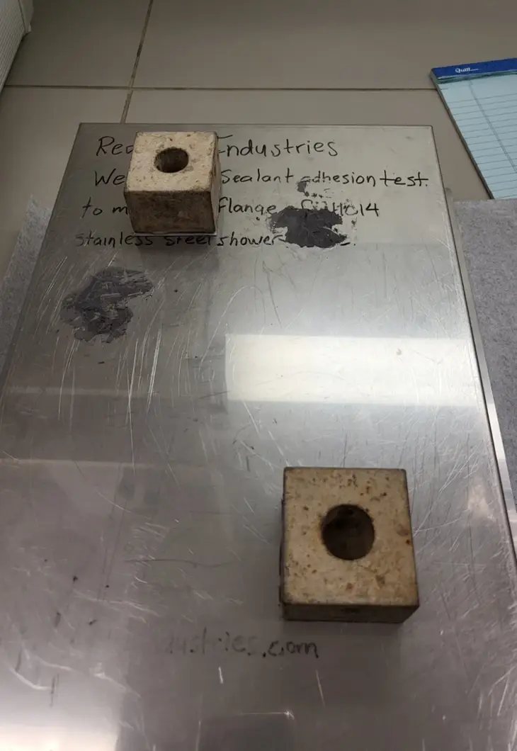 Wedi laboratory photograph from Product/Process Test Report 2101 documenting tensile-bond testing of the membrane-to-stainless-steel interface.