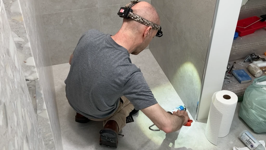 Caulking the shower corners with silicone sealant