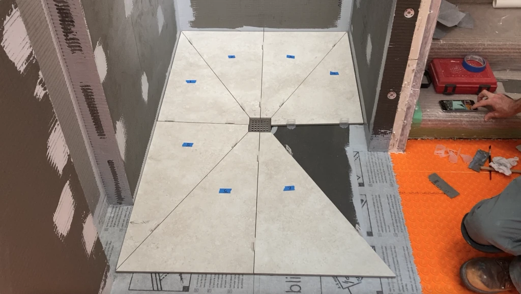 Dry-fitting large format shower floor tile around drain on Wedi shower tray